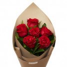 Bouquet of seven red roses with green leaves wrapped in tan kraft paper