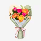 Vibrant bouquet with orange gerberas, pink roses, and greenery wrapped in sage paper with pink ribbon