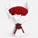 Luxurious bouquet of 100 red roses wrapped in white paper with burgundy ribbon bow