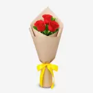 Bouquet of three red roses wrapped in beige paper with yellow ribbon bow