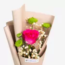 Vibrant pink rose bouquet with green chrysanthemums and white baby's breath in kraft paper wrapping