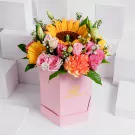 Colorful flower arrangement with yellow sunflowers, pink roses, and orange gerberas in pink box