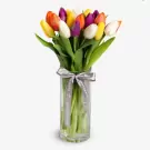 Colorful assorted tulips in glass vase with purple ribbon bow arrangement