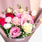 Colorful bouquet of pink carnations, red roses, yellow roses and white daisies in mauve wrapping