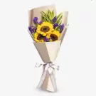 Sunflower bouquet with yellow blooms, purple statice, and green foliage in cream paper wrapper