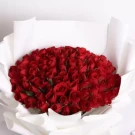 Luxurious bouquet of 100 vibrant red roses arranged densely in white wrapping paper