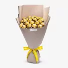 Bouquet of golden wrapped chocolates in beige paper with yellow ribbon bow
