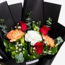 Elegant black-wrapped bouquet featuring red roses, orange proteas, white carnations, and greenery