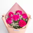 Vibrant magenta roses with white daisies in peach wrapping paper bouquet