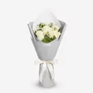 Elegant white roses bouquet with green foliage in gray wrapping and cream ribbon