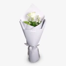 White rose bouquet with baby's breath and greenery wrapped in lavender paper