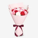Pink wrapped bouquet of red, pink, and white carnations with burgundy ribbon bow