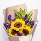 Yellow sunflowers with purple statice and green foliage in cream paper wrapping