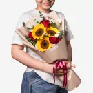 Sunflower bouquet with red roses, white flowers, and eucalyptus in beige wrapping
