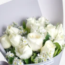 White roses with small white daisy flowers arranged in elegant white wrapping paper