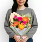 Vibrant bouquet with orange gerberas, pink roses, and white filler flowers in green wrap