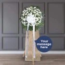 White floral standing spray with green foliage and burlap wrap on easel