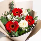 Red gerberas, white roses, and daisies in cream paper wrap bouquet