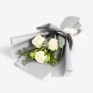 Elegant white roses with green foliage wrapped in gray paper bouquet