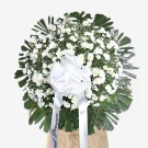 White roses and daisies with green foliage in round standing funeral arrangement