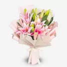 Pink and white lilies with green buds in cream wrapping, tied with ribbon