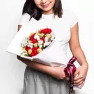 Woman holding bouquet of red roses and white chrysanthemums with burgundy ribbon