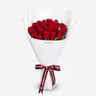 Luxurious bouquet of 24 red roses wrapped in white paper with burgundy ribbon