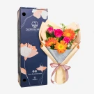 Vibrant bouquet of orange gerberas and pink carnations with cream wrapping and pink bow