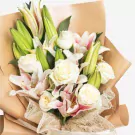 Elegant bouquet of white roses, pink orchids, and green lily buds wrapped in kraft paper