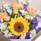 Sunflower bouquet with peach carnations, white daisies, purple statice, and gold accents