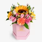 Vibrant pink hexagonal box with yellow sunflowers, pink roses, and coral carnations