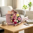 Vibrant mixed flower bouquet with pink, red, and yellow blooms wrapped in mauve paper