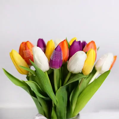 Colorful assorted tulips bouquet with orange, yellow, purple, and white stems in vase arrangement