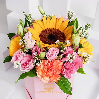Vibrant bouquet with yellow sunflowers, pink roses, and coral carnations in a pink box
