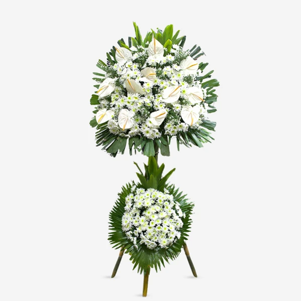 White flower sympathy standing spray with lilies, daisies, and green foliage