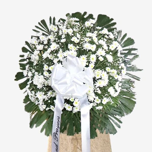 White roses and daisies with green foliage in round standing funeral arrangement