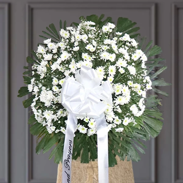 White daisies and roses with green foliage in sympathy standing spray arrangement