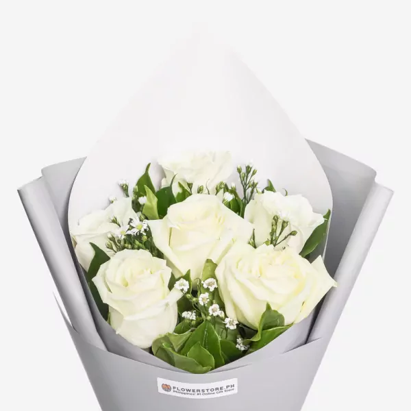 White roses with green foliage wrapped in gray paper bouquet arrangement