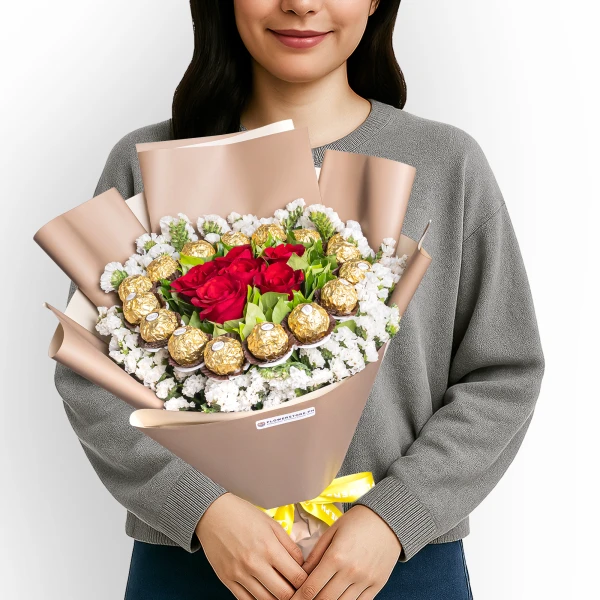 Woman holding bouquet with red roses, white flowers, and gold chocolate candies in beige wrapping