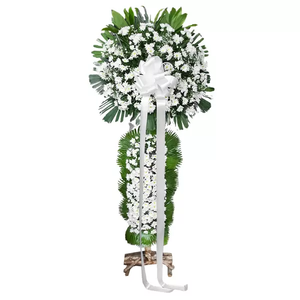 White floral standing spray with green foliage and white ribbon bow