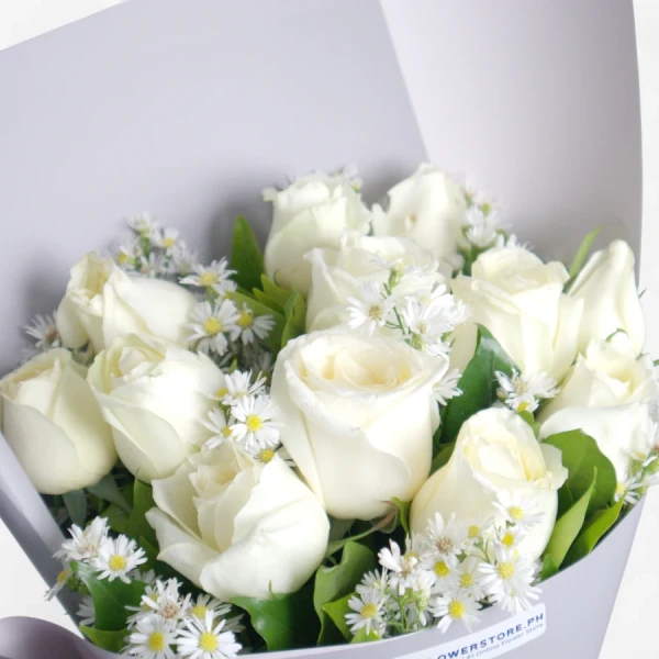 White roses with small white daisy flowers arranged in elegant white wrapping paper