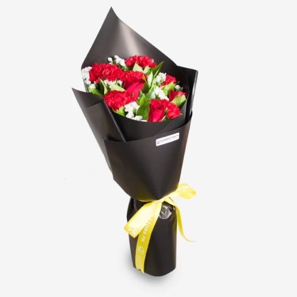 Red and white carnations bouquet wrapped in black paper with yellow ribbon