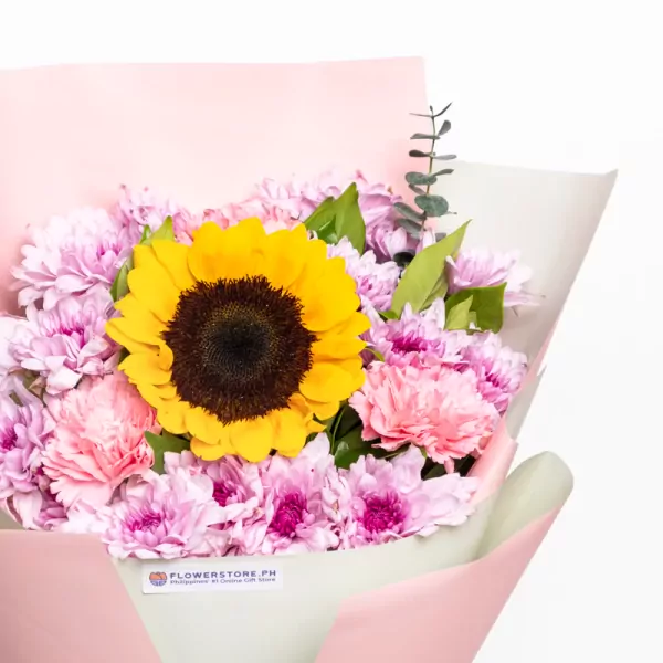 Vibrant sunflower surrounded by pink carnations and eucalyptus in pastel wrapping