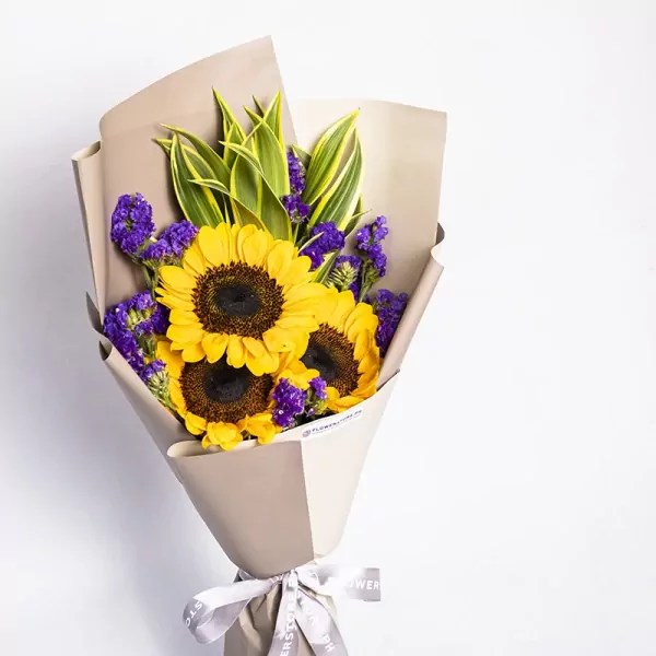 Bright sunflower bouquet with purple statice and green foliage wrapped in kraft paper