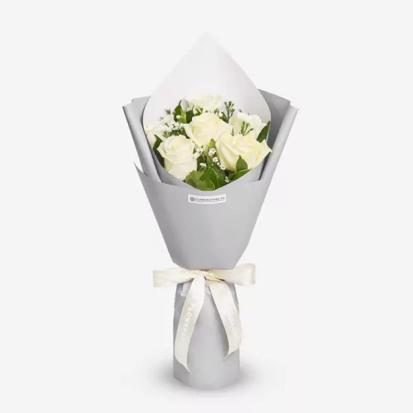 Elegant white roses bouquet with green foliage in gray wrapping and cream ribbon