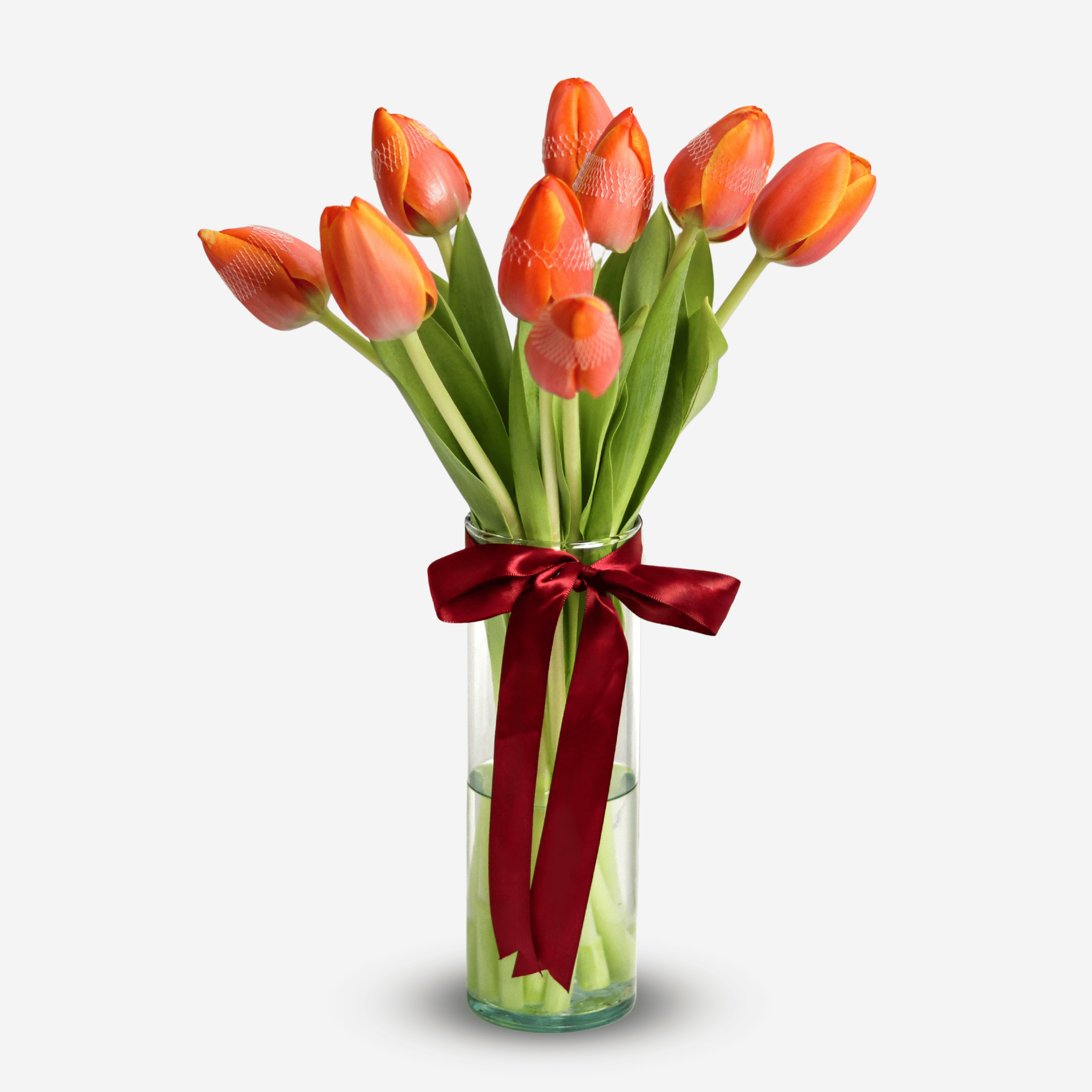 This arrangement includes 10 stems of red-orange tulips presented in a glass vase.