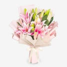 Pink lilies in a bouquet with pink and beige wrapping, tied with a cream ribbon.