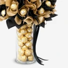 Ferrero Rocher chocolates in a glass vase with gold and black decorative paper.