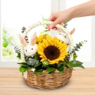 Easter basket with sunflowers and bunny decorations, held by a person's hand.