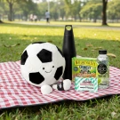 Plush football, water bottle, granola bars, and mints on a picnic blanket.
